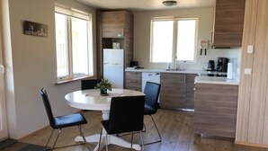 Una cocina moderna con armarios de madera, un refrigerador blanco y un comedor con una mesa redonda y dos sillas.