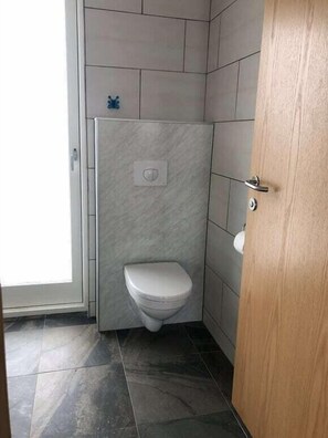 Un baño pequeño con inodoro, ducha y puerta.