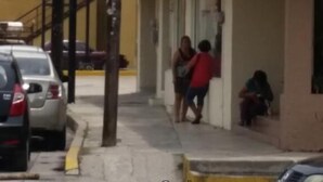 Um hotel chamado 'Bonito Inn' com uma placa indicando que é um hotel. Pessoas podem ser vistas do lado de fora do edifício, e um carro estacionado nas proximidades.