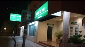Entrada de hotel com uma placa indicando "BONITTO INN" e uma placa de "CAFETERIA".