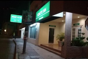 Entrada de un hotel con un letrero que dice "BONITTO INN" y un letrero de "CAFETERÍA".