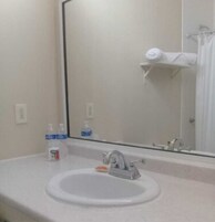 Un baño con lavamanos, espejo y perchero para toallas.