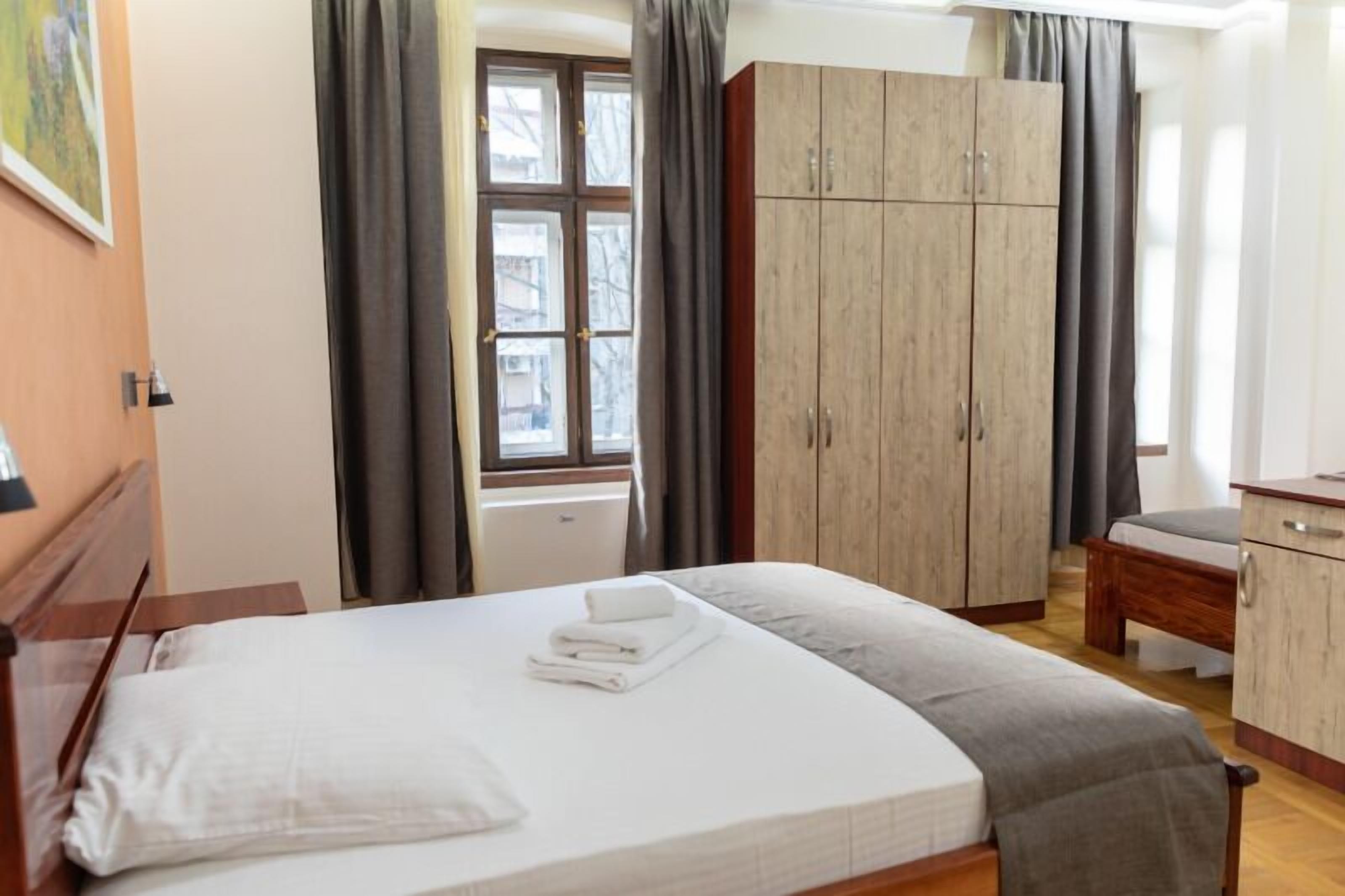 A hotel room with a bed, a wardrobe, a desk, and a window.