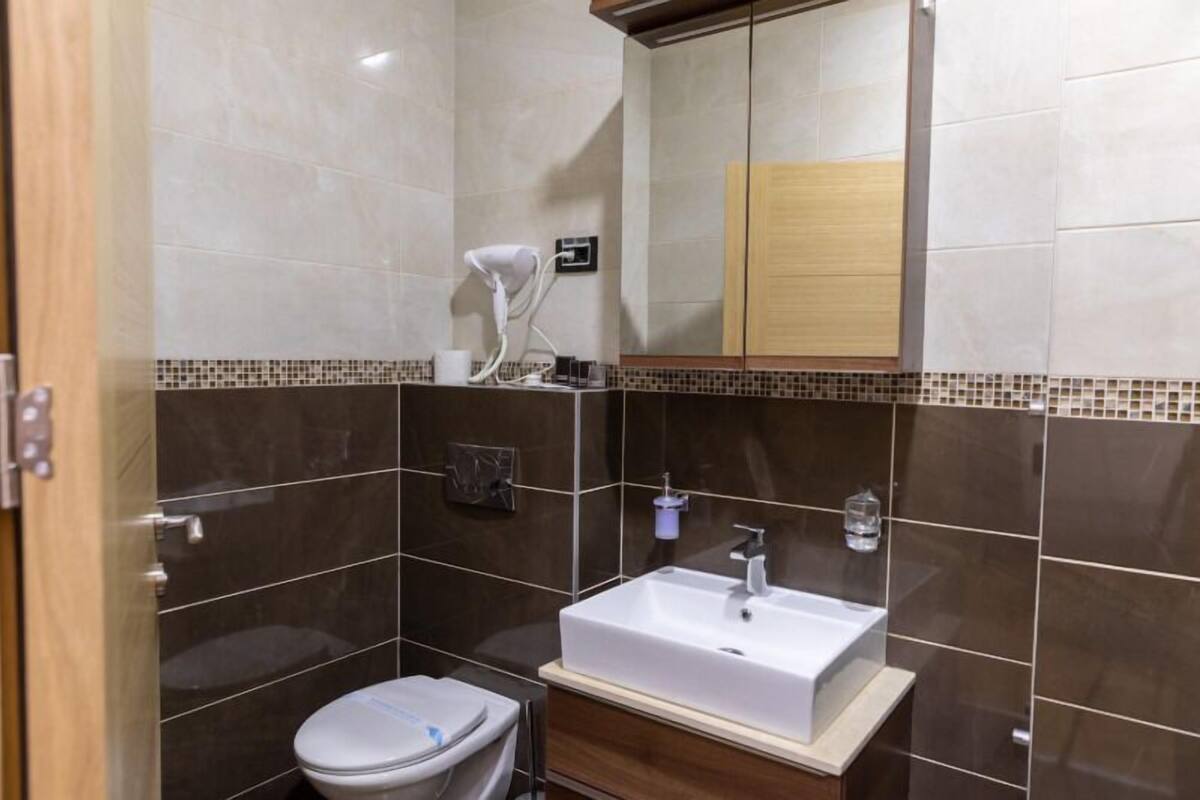 A modern bathroom with a white sink, a toilet, and a mirror.