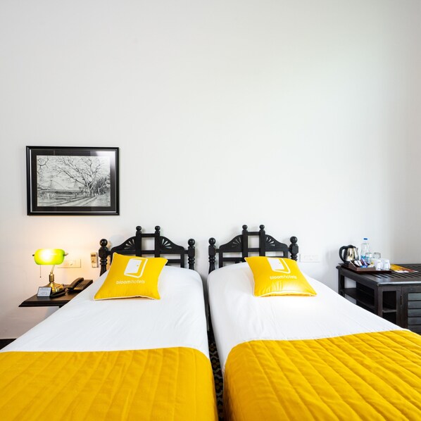 A hotel room with two beds, each with a yellow pillow and a framed picture on the wall.