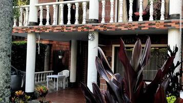 Un bâtiment à deux étages doté d’un balcon, de colonnes et de plantes en pot.