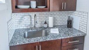 A kitchen with dark wooden cabinets, a granite countertop, and a stainless steel sink.