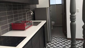 Une cuisine moderne avec des carreaux de couleur sombre, un évier en acier inoxydable et un appareil électroménager rouge.