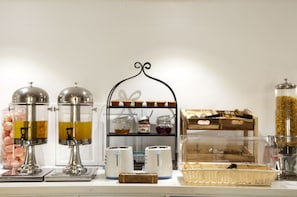 A breakfast buffet setup with various food items and condiments. - Bloomrooms @ Calangute (Calangute)