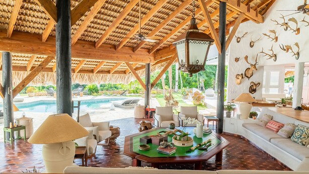 Un espacio interior amplio con piscina, techo de madera y diferentes opciones de asientos.