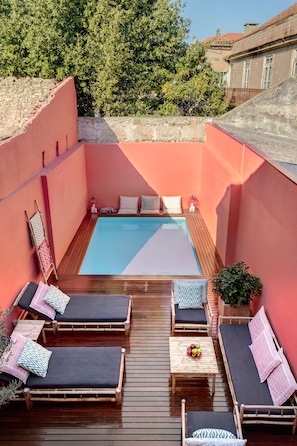 A rooftop pool area with wooden loungers and a small table with fruit. - Casa da Praça (Porto)