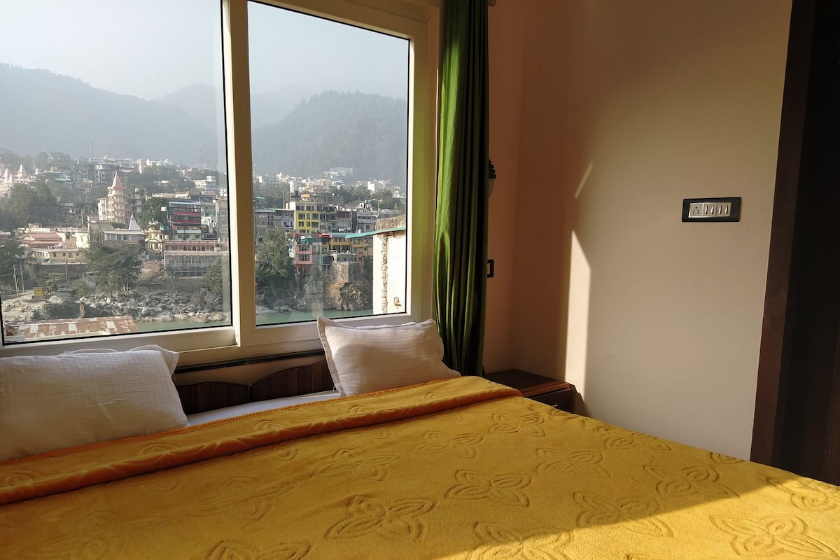 A hotel room with a bed, a window, and a view of a cityscape.