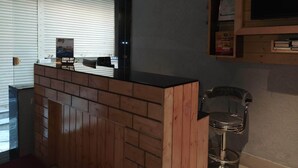 Zona de recepción con mostrador de madera, separador de vidrio y cámara de seguridad instalada.