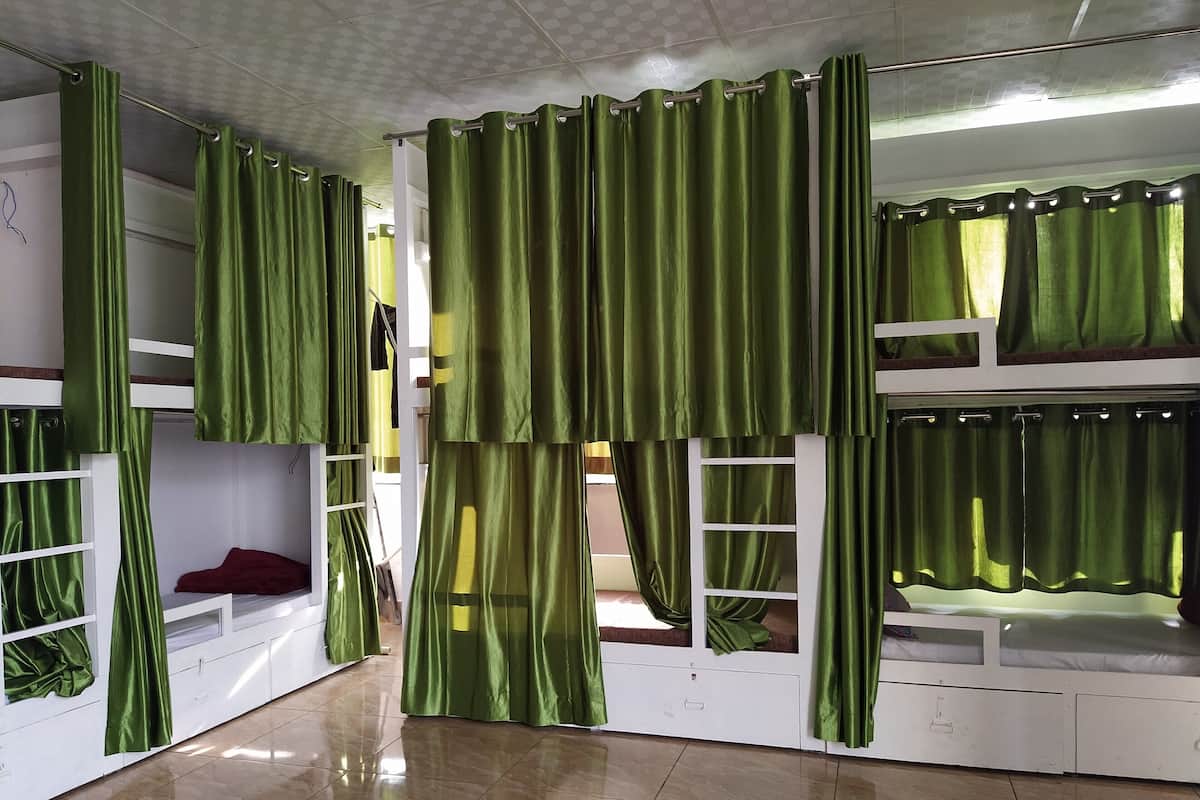 A bunk bed room with green curtains and a tiled floor.