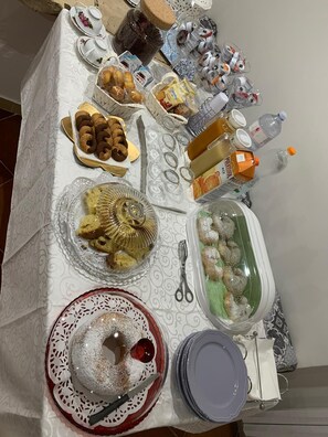 A table set with various food items, including pastries, a cake, and condiments. - Maison Rinaldi (Bari)