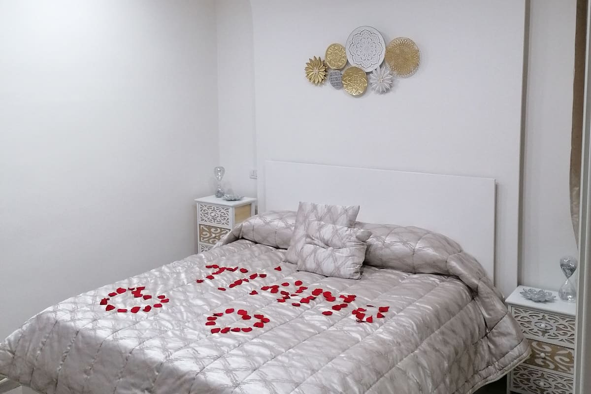 Quarto com cama, mesa de cabeceira, arte decorativa na parede e claraboia.