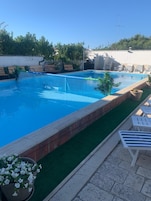 Une piscine à l’eau d’un bleu cristallin, entourée d’un espace aménagé avec des chaises longues et des plantes en pot.