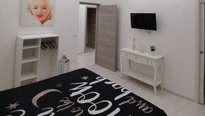A modern bedroom with a bed, a TV, a wardrobe, and a shoe rack. - Maison Rinaldi (Bari)