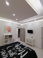 Une chambre moderne comprenant un lit, une télévision, une armoire et un porte-chaussures.