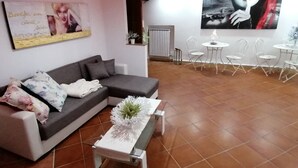 A modern living room with a grey sectional sofa, a white coffee table with a floral centerpiece, and a red accent wall. - Maison Rinaldi (Bari)