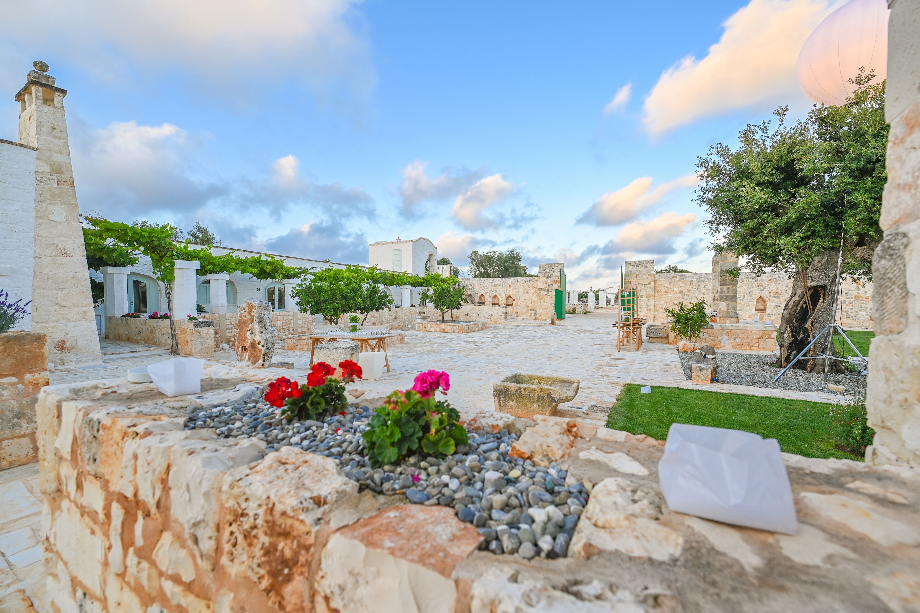 An outdoor courtyard with stone walls, a grassy area, and a few potted plants.