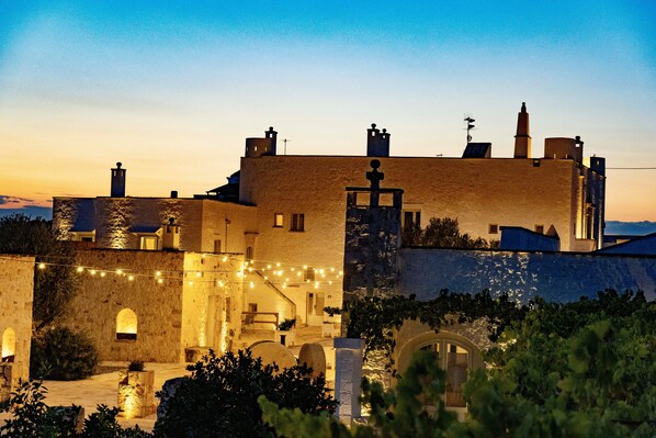 A historic building with arched doorways and a courtyard at dusk. - Masseria Ayroldi (Ostuni)