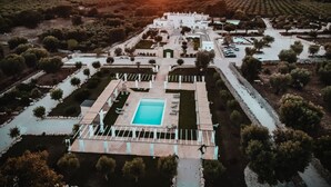 Vista aérea de un complejo turístico con una piscina central, rodeado de senderos y vegetación.