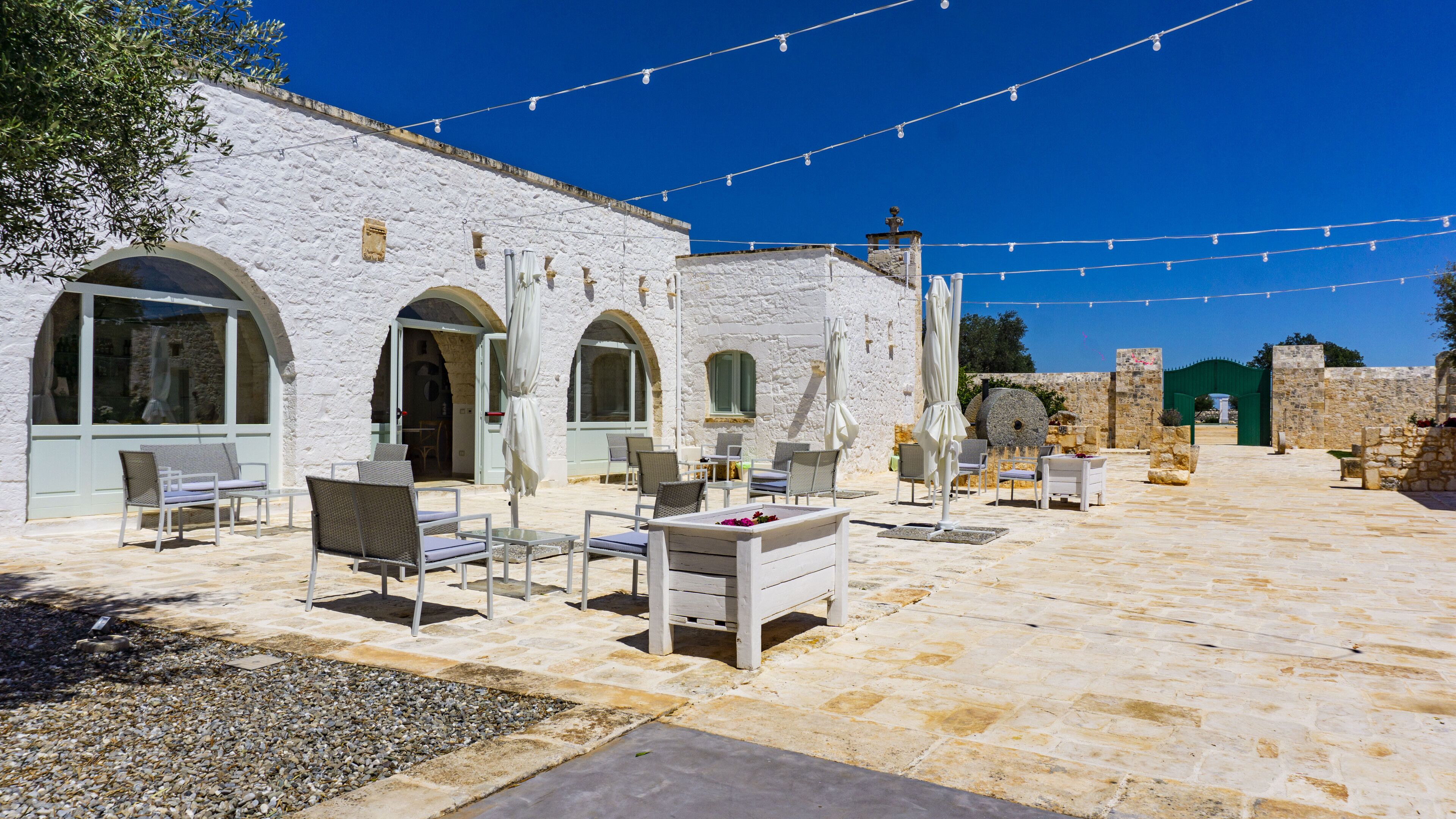 Un edificio de piedra blanca con terraza y luces colgantes.