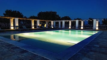 A rectangular swimming pool with a pergola and lounge chairs.