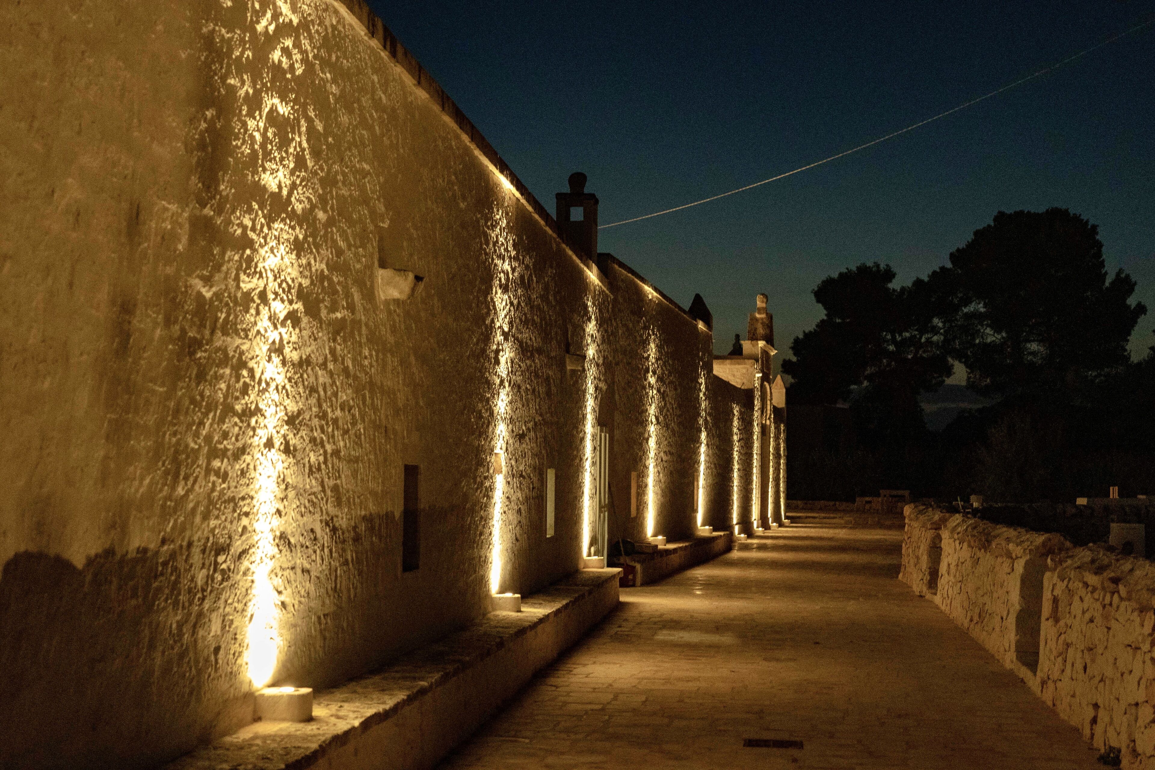 Un couloir aux murs de pierre, bordé d’une série de colonnes illuminées.