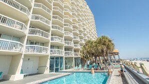 A hotel with multiple balconies, a swimming pool, and a beach view.