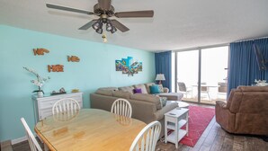 A living room with a dining table, sofa, and a ceiling fan.