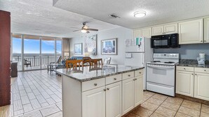 A kitchen with a large island, white cabinets, a microwave, stove, and a view to the outside. - 1206 Waters Edge Resort 1 Bedroom Condo by RedAwning (Murrells Inlet)