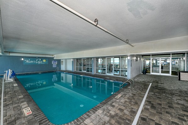 An indoor swimming pool with clear water, a tiled floor, and a sign reading "Water's Edge Resort". - 0610 Waters Edge Resort 1 Bedroom Condo by RedAwning (Murrells Inlet)
