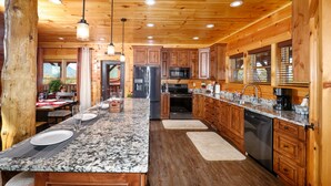 Una cocina amplia con armarios de madera, encimeras de granito y electrodomésticos de acero inoxidable.