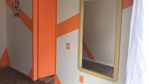 A hallway with an orange door and a mirror on the wall. - Pousada Praia do Trapiche (Penha)