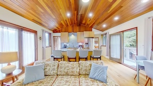 Uma sala de estar aconchegante com sofá, mesa de jantar e cozinha equipada com geladeira e pia.