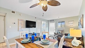 A dining area with a wooden table, blue glassware, and a television in the background. - August Specials! 3 night min! 2bed2 Bath-Walk to Beach-Indoor Pool! (Hilton Head Island)