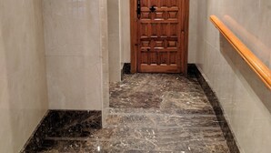 A hallway with marble flooring, a wooden door, and a wooden handrail. - Great Apt near Atocha 3hab 2b (Madrid)