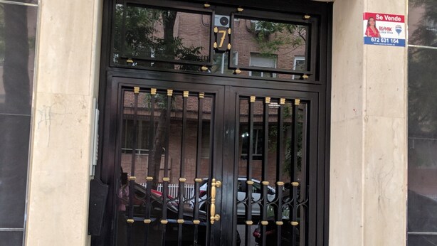 A black metal gate with a number 7, a sign advertising real estate, and a small step leading to the entrance. - Great Apt near Atocha 3hab 2b (Madrid)