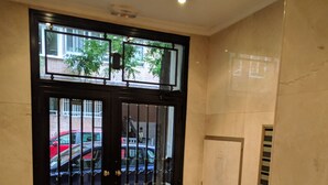 A black door with metal bars, a marble floor, and a wall-mounted vent. - Great Apt near Atocha 3hab 2b (Madrid)
