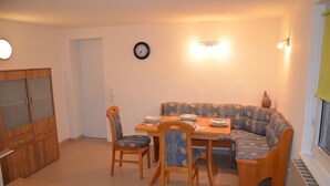 Een zithoek met een bank, stoelen, een tafel en een klok aan de muur.
