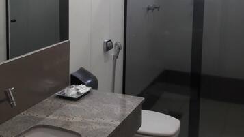 Un baño moderno con un espejo grande, encimera de granito, inodoro y cabina de ducha de vidrio.