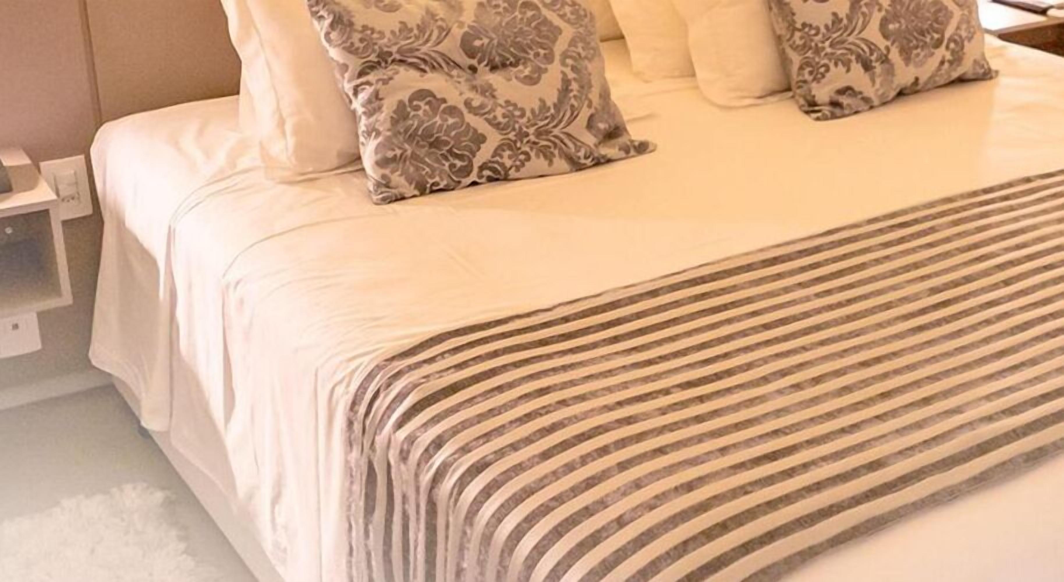 A neatly made bed with a striped bedspread and patterned pillows.