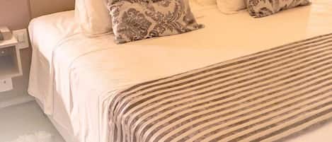 A neatly made bed with a striped bedspread and patterned pillows.