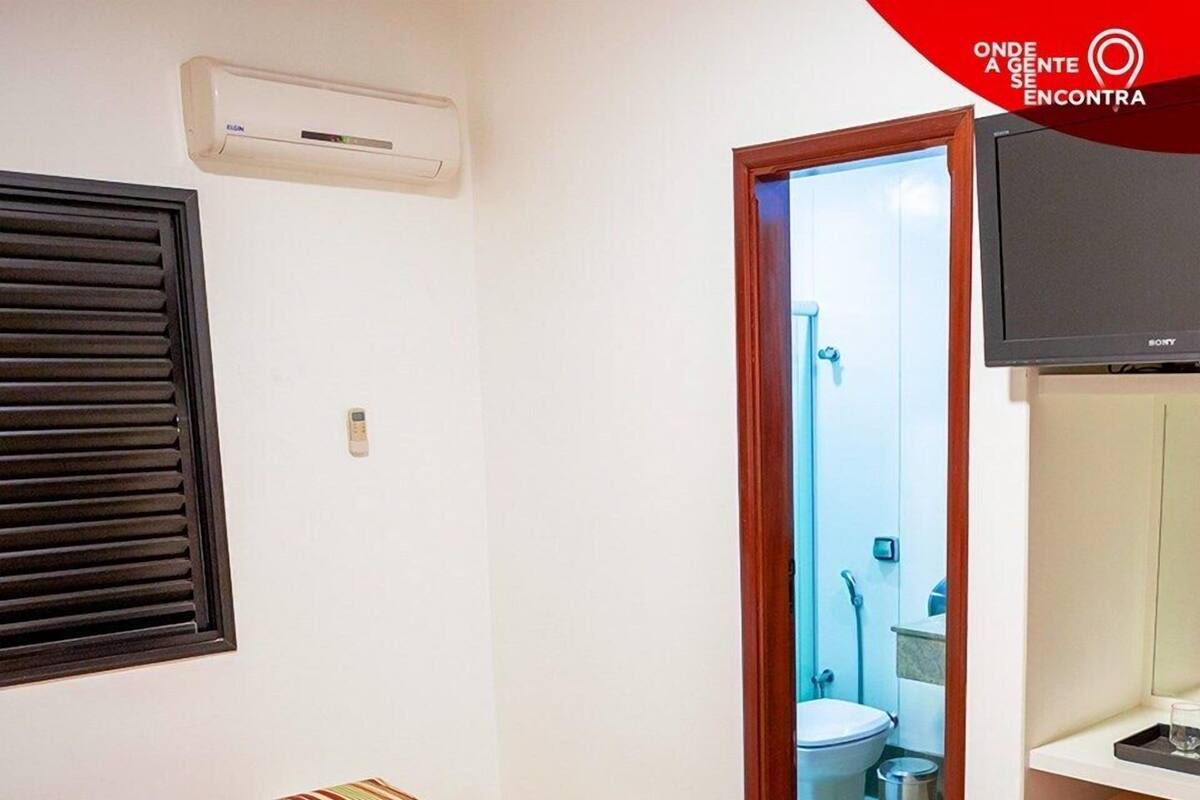 A hotel room with a bed, a TV, and a bathroom visible through an open door.