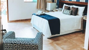 A hotel room with a bed, bedside table, lamp, and a view of greenery outside. - Pousada Oceano (Ipojuca)