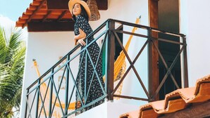 A balcony with a tiled roof, a metal railing, and a window. - Pousada Oceano (Ipojuca)