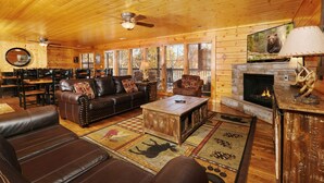 L’intérieur d’un chalet chaleureux, avec un canapé en cuir, une table basse et une cheminée.
