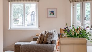 Ein Wohnzimmer mit einer Couch, einem kleinen Tisch mit einer Flasche und einer Vase mit Blumen.